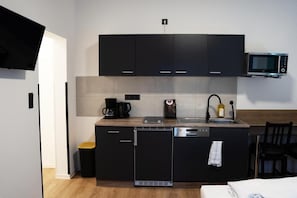 Eine kleine Küche mit Mikrowelle, Kaffeemaschine und Geschirrspüler.