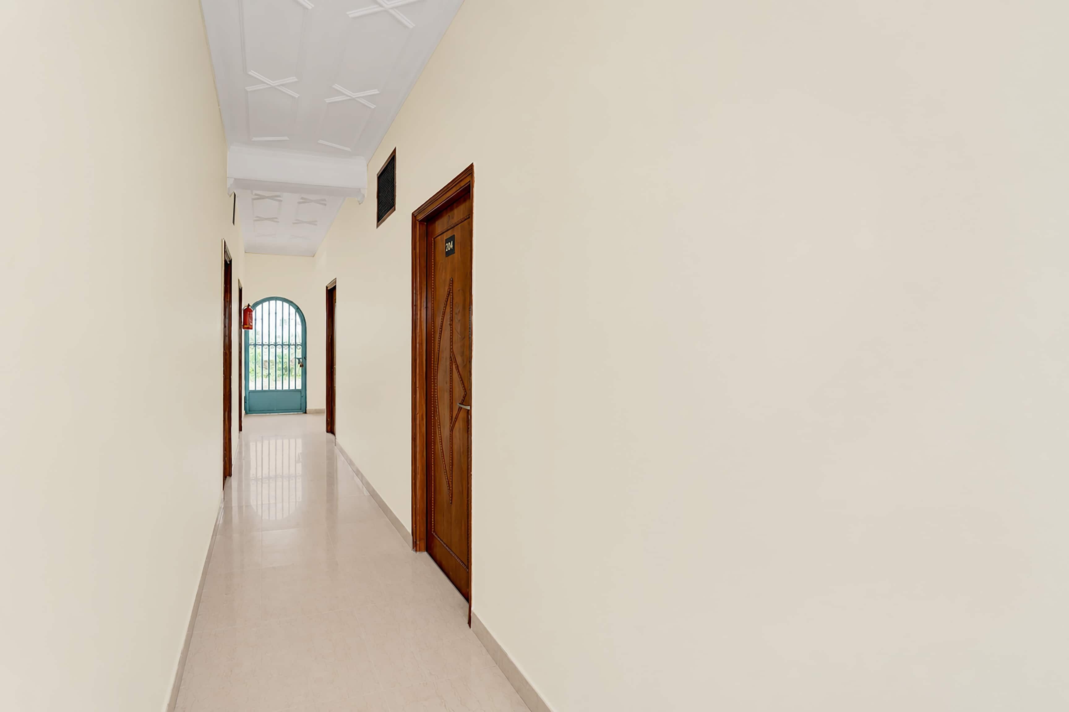 Un couloir avec une porte en bois, une fenêtre dotée d’un cadre bleu et un plafond orné d’un motif géométrique.