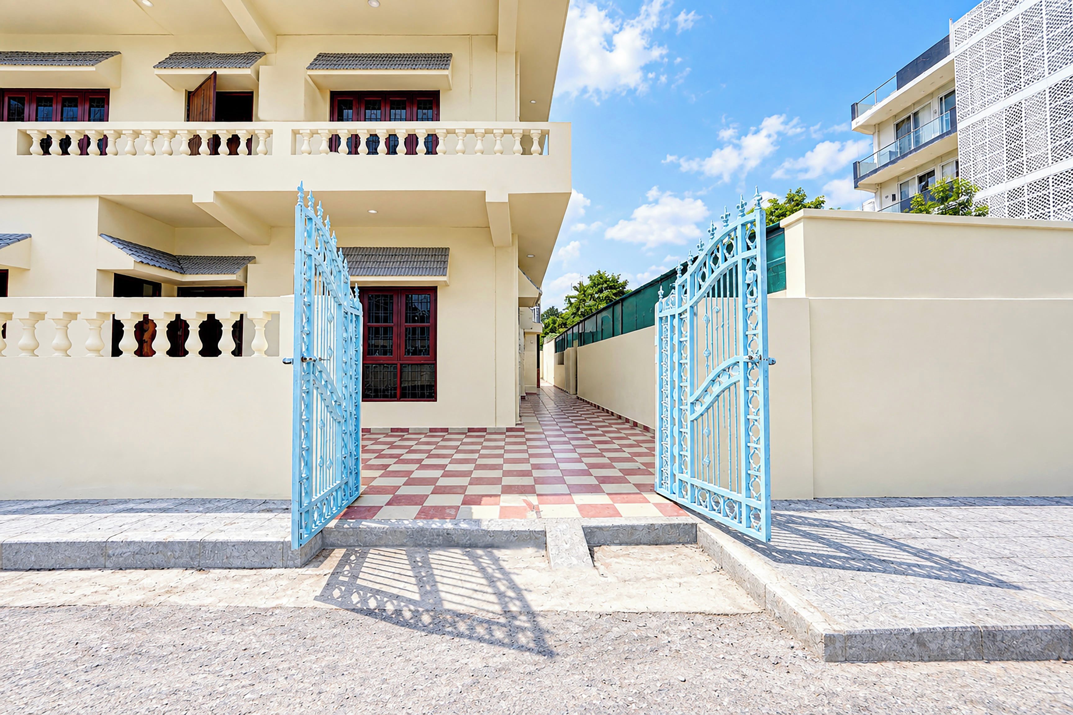 A two-story building with a checkered floor pattern leading to a blue gate.