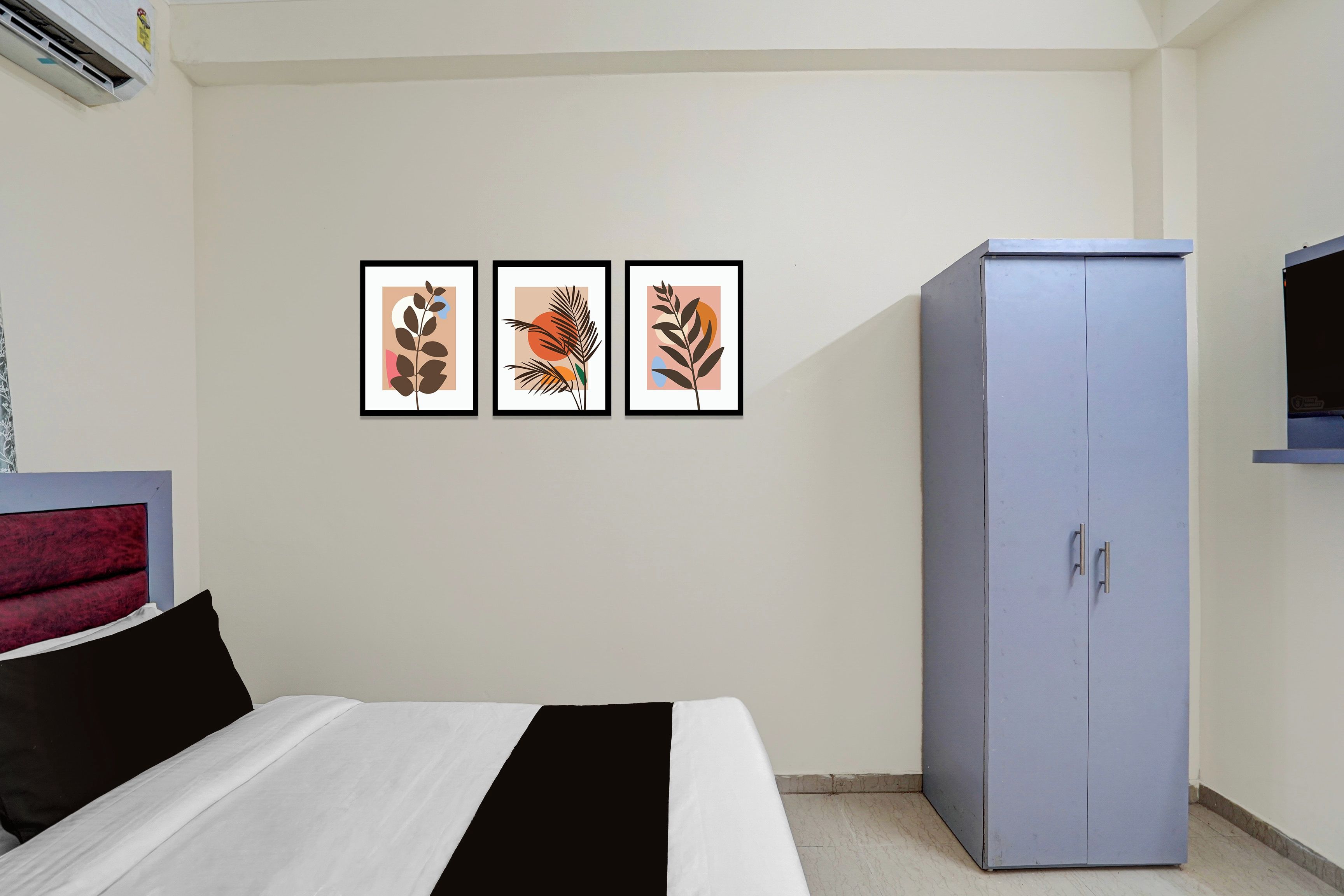Un dormitorio con cama, armario y tres láminas enmarcadas con motivos vegetales en la pared.