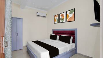 A bedroom with a bed, a wardrobe, a flat-screen TV, and an air conditioning unit.