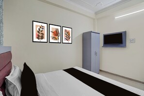 A bedroom with a bed, a wardrobe, and a TV mounted on the wall. - otel O Uttaranchal University Road (Dehradun)
