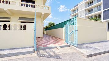 A gated entrance to a residential building with a checkered floor pattern leading to a balcony.