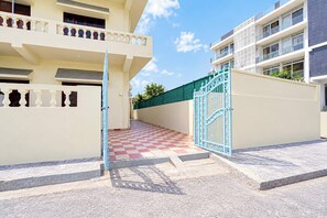 A gated entrance to a residential building with a checkered floor pattern leading to a balcony. - otel O Uttaranchal University Road (Dehradun)