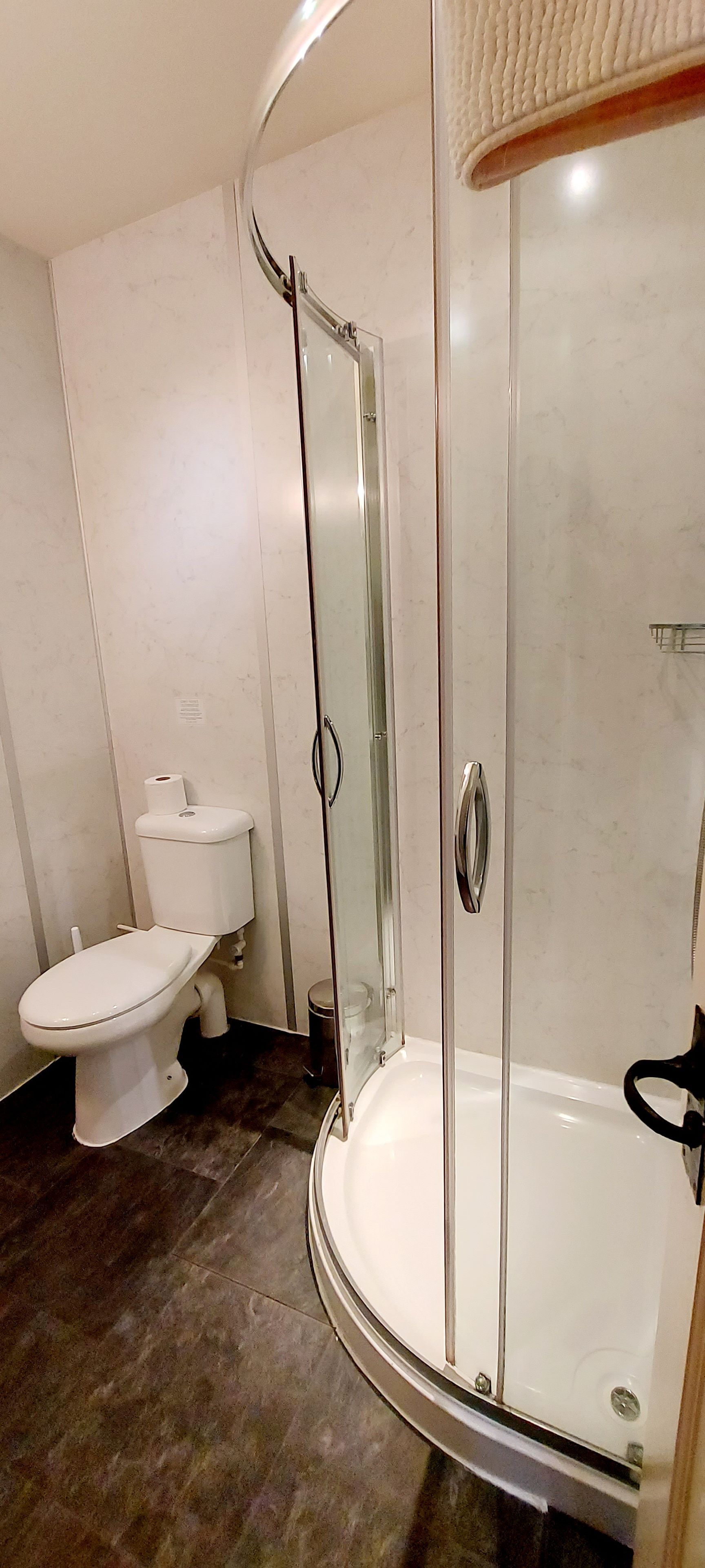 A bathroom with a glass-enclosed shower, a toilet, and a sink.