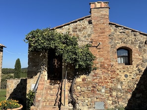 Un bâtiment en pierre doté d’une cheminée, d’une fenêtre et d’une porte.