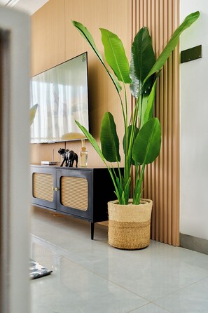 A modern living room with a large flat-screen TV, a woven plant stand, and a decorative elephant figurine. - The Big Five with Sunrise and Stunning Panoramic Night Views (Nairobi)