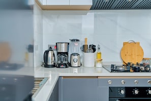 Eine moderne Küche mit Kaffeemaschine, Mixer, Wasserkocher und Schneidebrett auf der Arbeitsfläche.