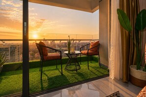 A balcony with a city view, two chairs, a table, and a potted plant. - The Big Five with Sunrise and Stunning Panoramic Night Views (Nairobi)