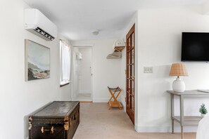A hallway with a vintage trunk, a coat rack, a television, and a lamp. - 2BR Coastal Retreat w/ River & Sea Views (Jenner)