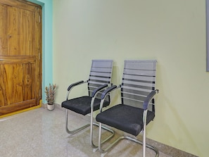 Ein Zimmer mit zwei Bürostühlen, einer Holztür und einem kleinen Topfpflanzen.
