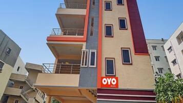 A multi-story building with balconies and a sign for 'OYO ROOMS'.