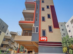 Ein mehrstöckiges Gebäude mit Balkonen und einem Schild mit der Aufschrift 'OYO ROOMS'.