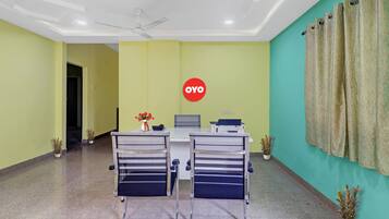 A conference room with two chairs, a table, a ceiling fan, and a wall-mounted sign.
