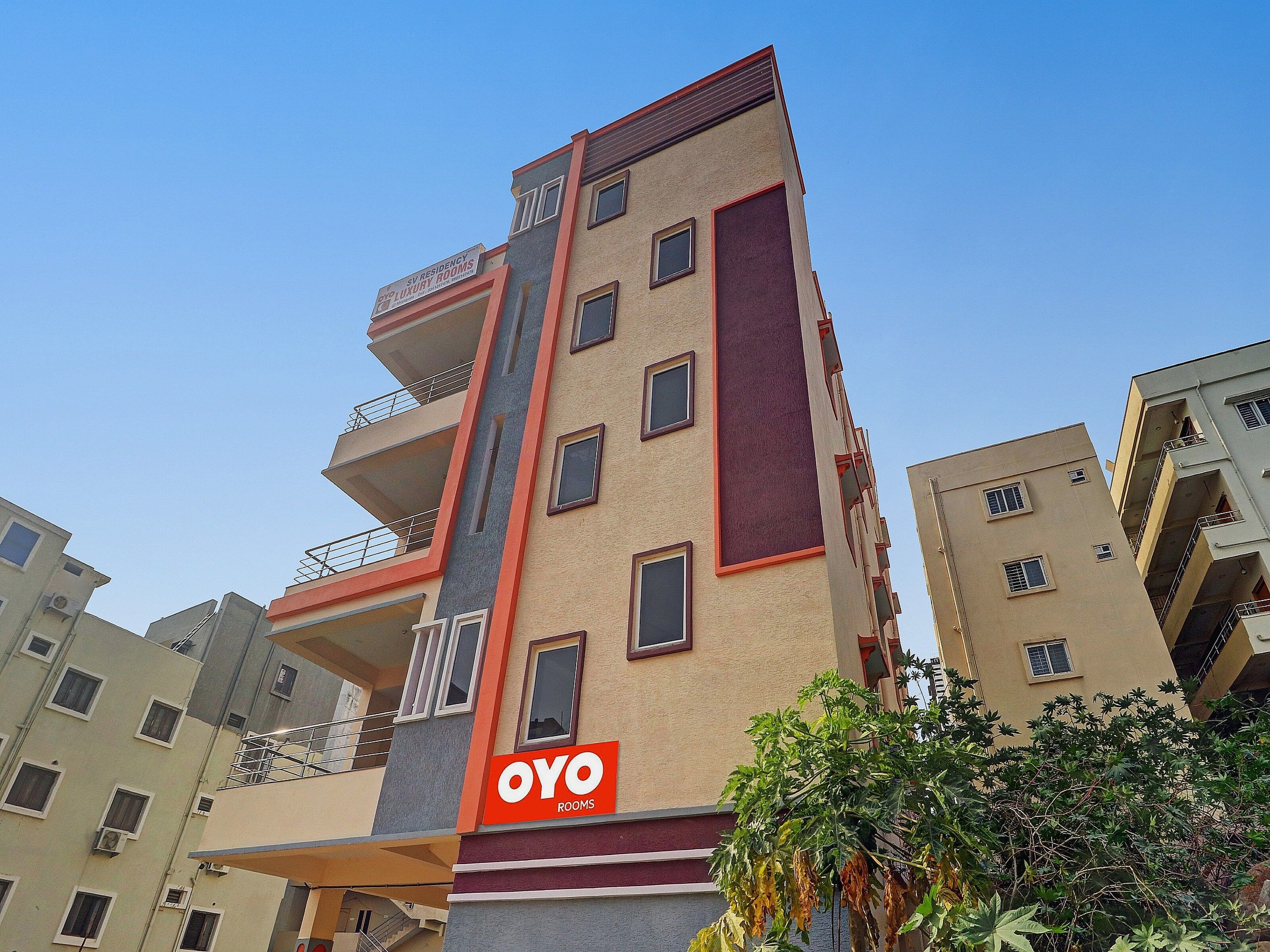 Un edificio de varios pisos con un llamativo letrero que dice 'OYO ROOMS' en la fachada.