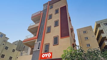 Un edificio de varios pisos con un llamativo letrero que dice 'OYO ROOMS' en la fachada.