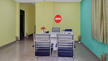 Een receptie met twee stoelen, een bureau, een printer en een vaas met bloemen.