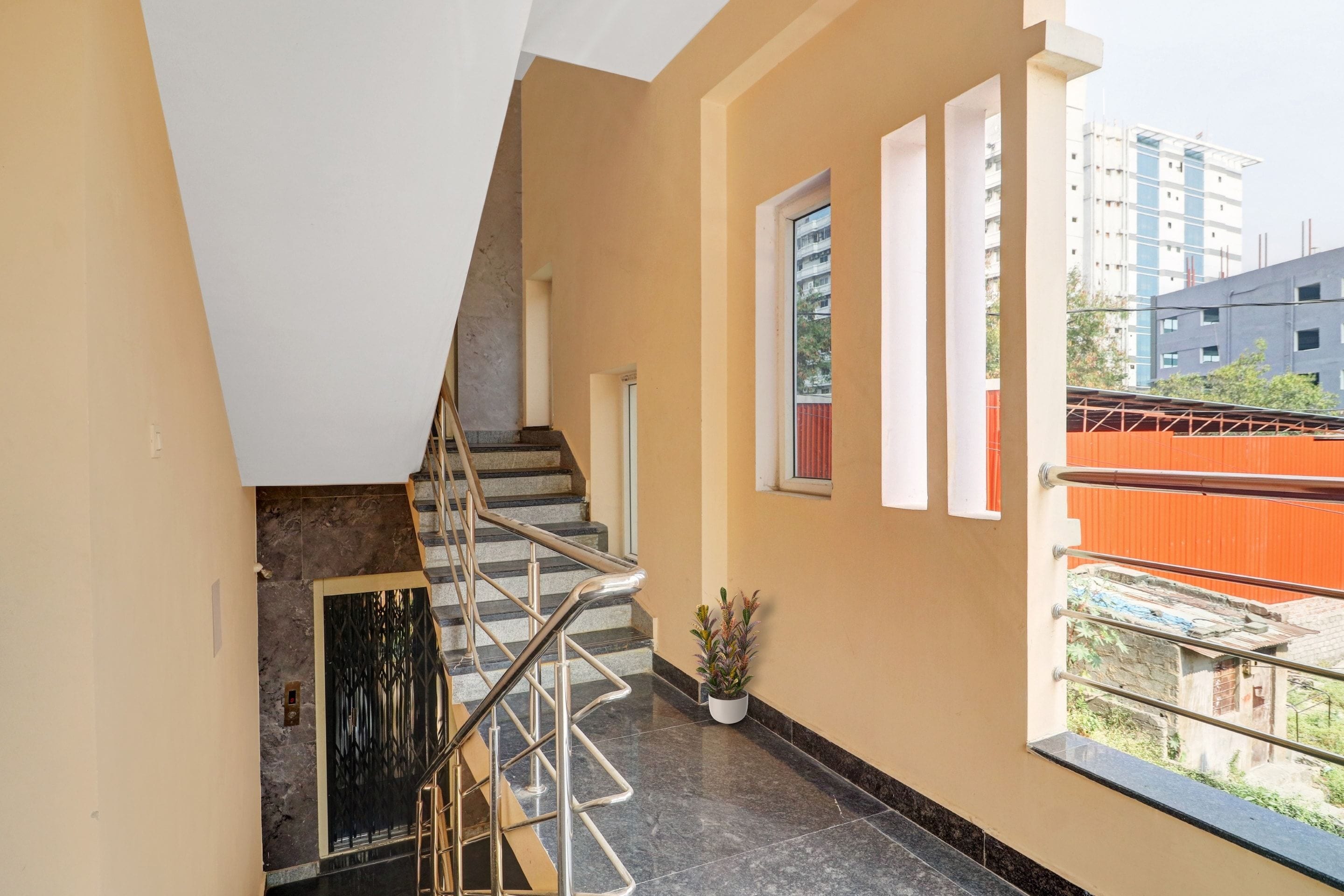 Una escalera con barandilla metálica que conduce a un rellano con una planta en maceta.