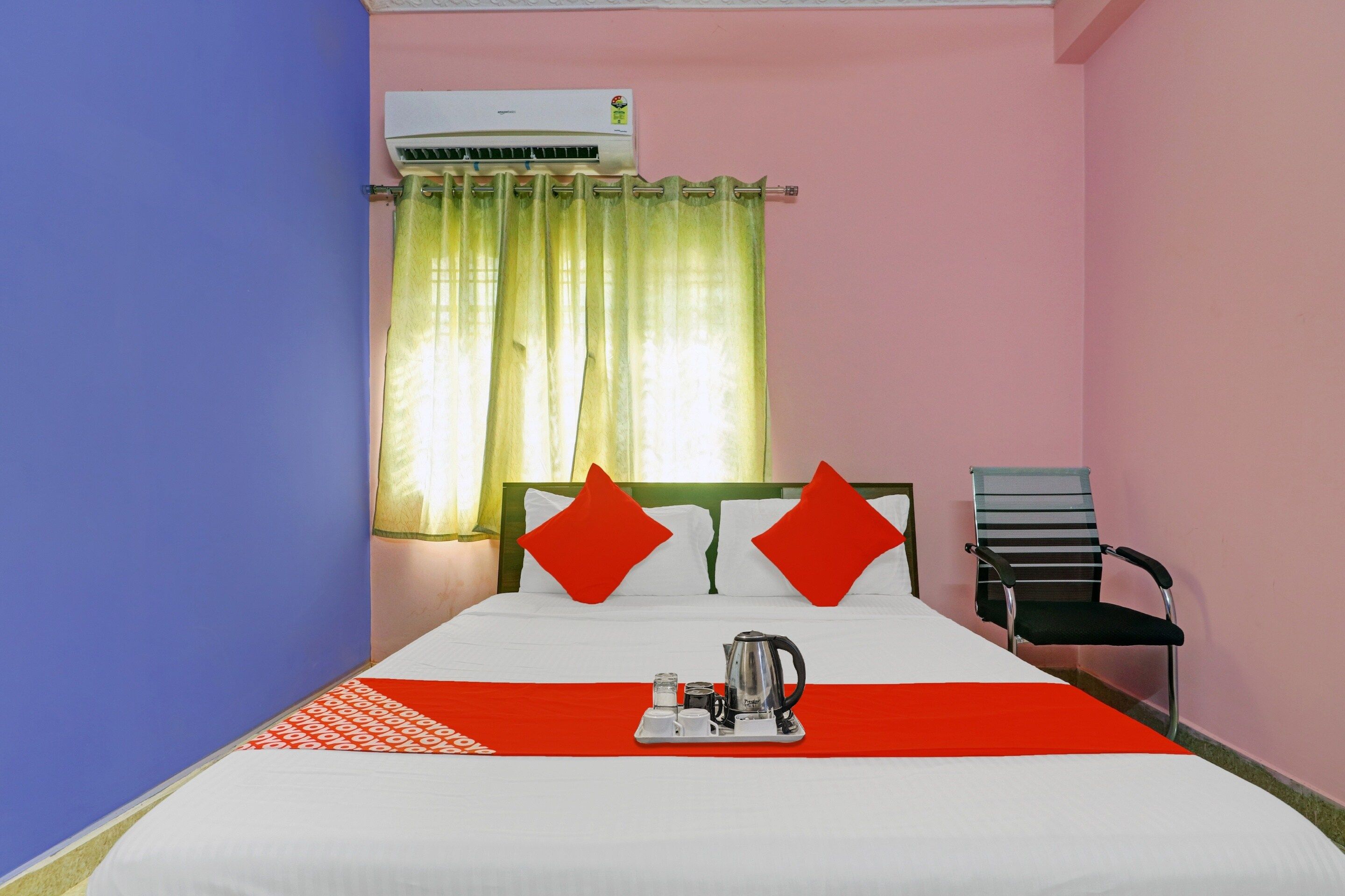 Una habitación de hotel con cama, una silla, cafetera y aire acondicionado.