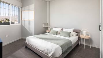 Un dormitorio moderno con una cama grande, mesitas de noche y una ventana con vistas.