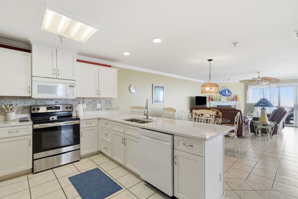 A modern kitchen with stainless steel appliances, a dining area with a table and chairs, and a view of the outdoors. - Oceanfront Views, Beach Steps Away, Walk Everywhere by Tybee Cottages (Tybee Island)
