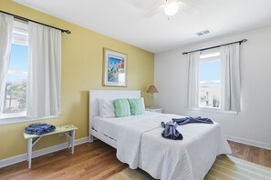 A bedroom with a bed, a nightstand, a lamp, and a window with curtains. - Oceanfront Views, Beach Steps Away, Walk Everywhere by Tybee Cottages (Tybee Island)