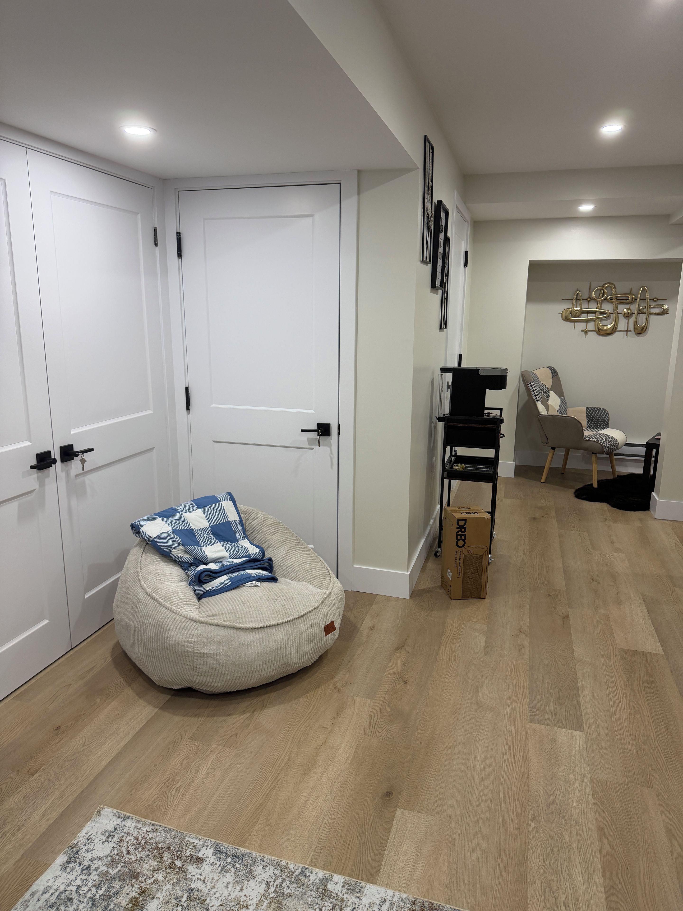 Une pièce comprenant un fauteuil en forme de sac de haricots, une petite table et une étagère fixée au mur.
