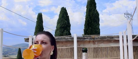 A person by a pool with a bottle of wine and a glass of orange juice.
