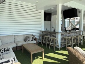 An outdoor seating area with a stone bar, a sofa, and a coffee table. - Ocean Isle Heaven: professional photos coming soon (Ocean Isle Beach)