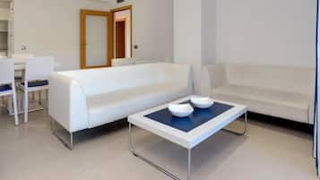Una sala de estar moderna con un sofá blanco, una mesa de centro con cuencos y un comedor con sillas.