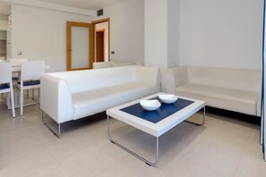 Ein modernes Wohnzimmer mit einem weißen Sofa, einem Couchtisch mit Schalen und einem Essbereich mit Stühlen.