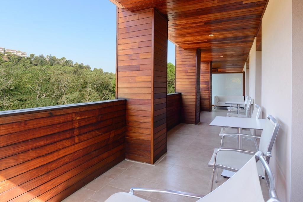 Zona relax esterna moderna con rivestimenti in legno e sedie in metallo, affacciata su un paesaggio verde.
