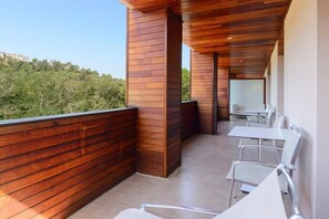 Ein moderner Außenbereich zum Sitzen mit Holzverkleidung und Metallstühlen, mit Blick auf eine grüne Landschaft.