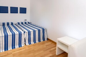 Ein Zimmer mit einem Bett, einem weißen Nachttisch und einem Wandregal.