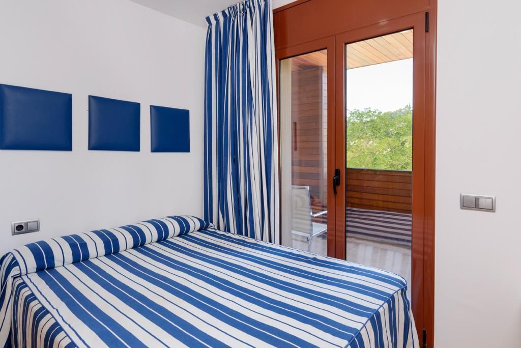 Een slaapkamer met een bed, een deur die leidt naar een balkon, en drie wandpanelen.