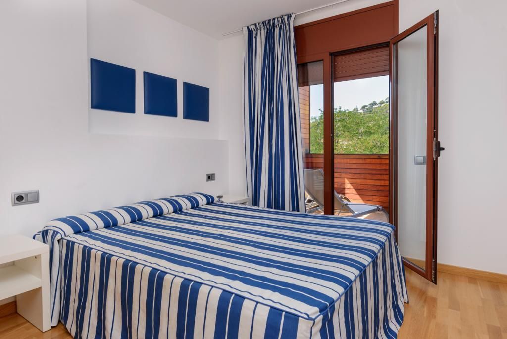 Une chambre avec un lit, un banc et une vue sur un balcon.