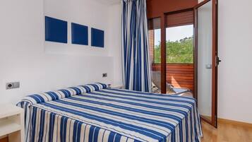 Un dormitorio con una cama, un banco y vistas a un balcón.