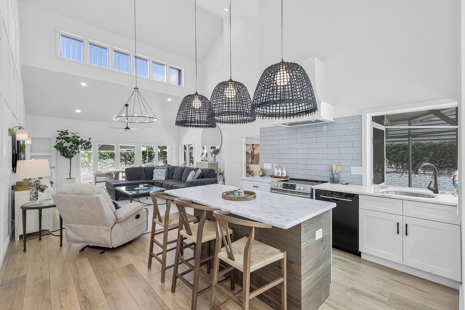 A modern kitchen with a central island, pendant lighting, and a view to the outdoors.