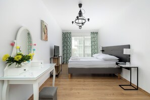 Habitación de hotel con cama, escritorio con espejo, televisor y candelabro.