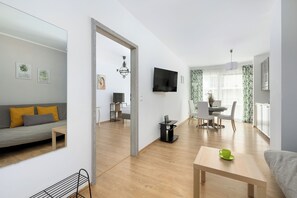 Un espacio habitable moderno con sofá, mesa de comedor y televisor montado en la pared.