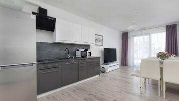 A modern kitchen with a built-in microwave, a large flat-screen TV, and a dining area with a table and chairs.