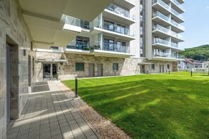 Un edificio moderno de varios pisos con patio, fachada de piedra y balcones de vidrio.