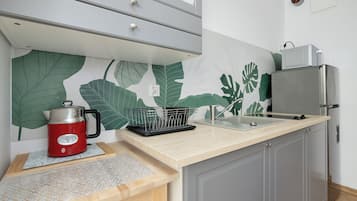 Une cuisine au design moderne, équipée d’un réfrigérateur en acier inoxydable, d’une bouilloire et d’un évier avec un plan de travail en bois.