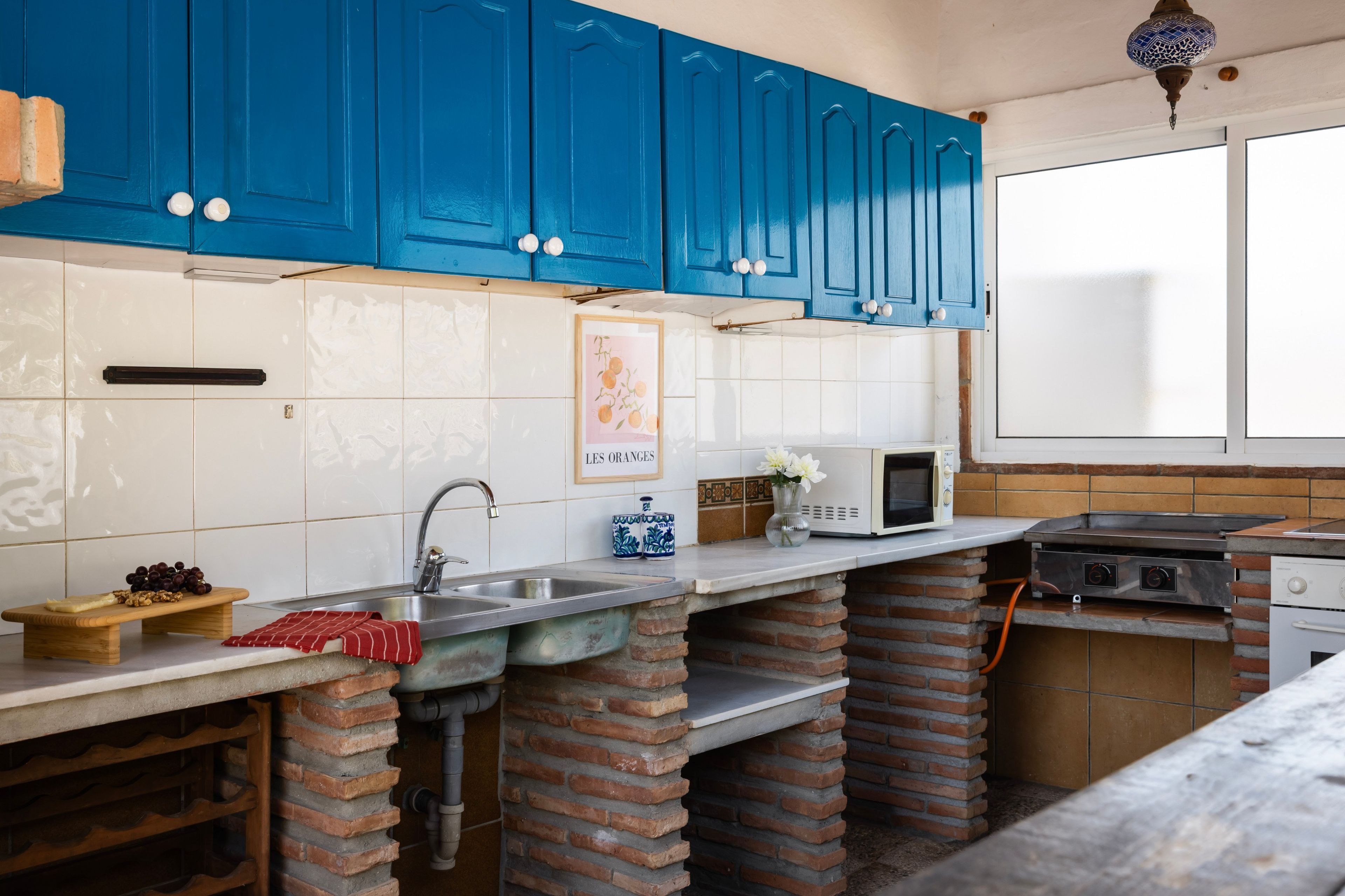 A kitchen with blue cabinets, a microwave, a stove, and a sink.