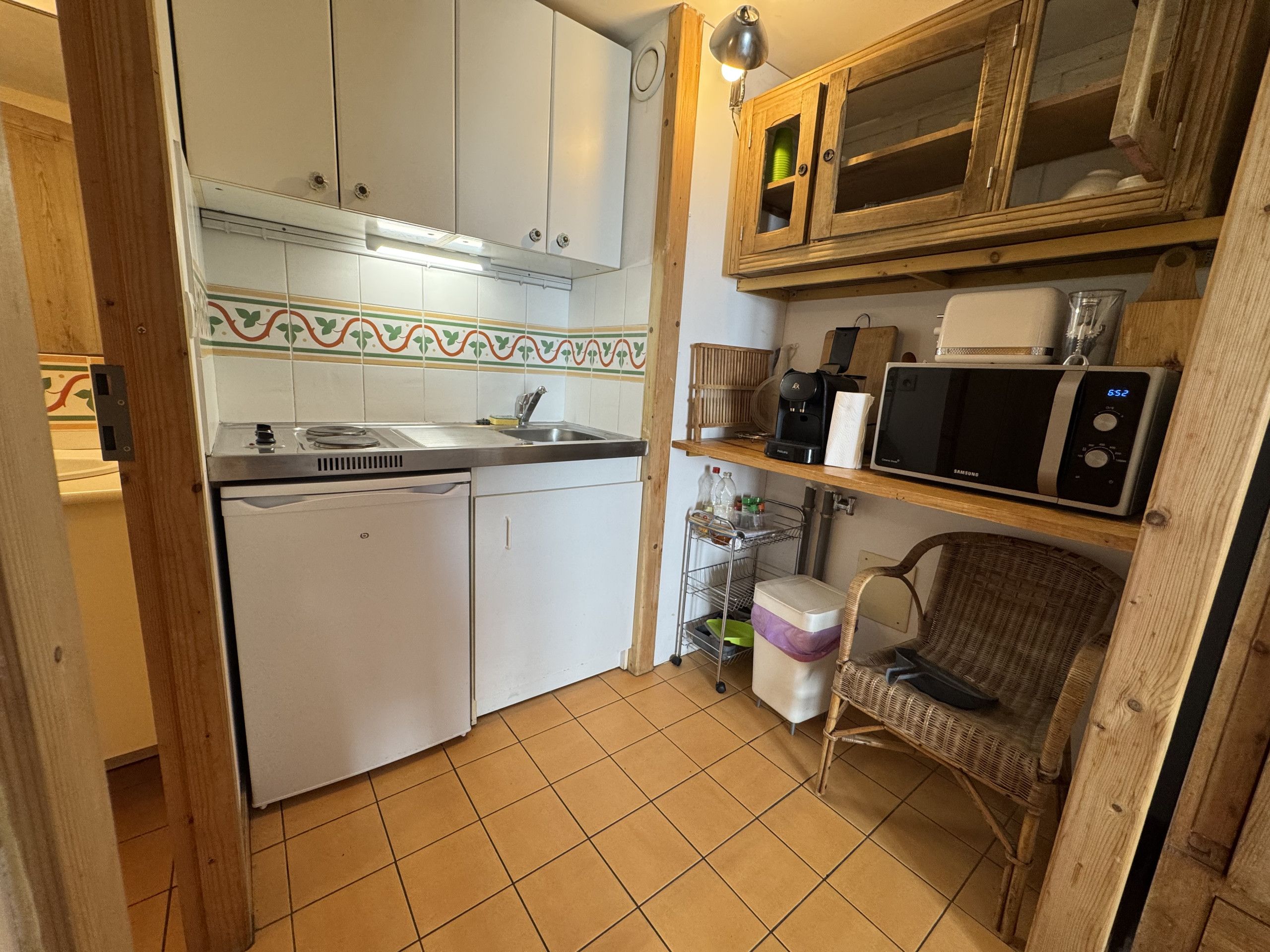 A compact kitchen with a white refrigerator, a microwave, and a coffee maker on the counter.