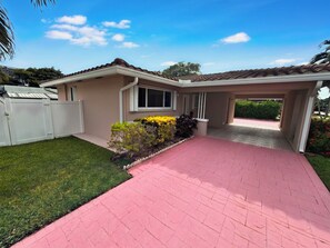 A residential house with a covered patio, a fenced yard, and a well-maintained lawn. - 3BR Hallandale Beach House, Fenced Yard & BBQ, Sleeps 8, Free Parking (Hallandale Beach)