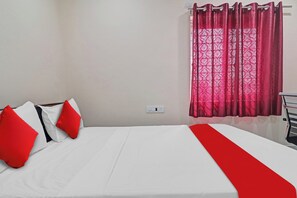 A bed with white bedding and red accents, a power outlet on the wall, and a window with red curtains. - Hotel O SV Grand (Hyderabad)