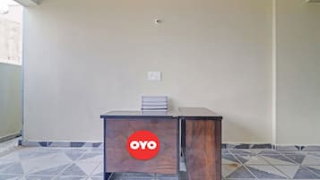 A room with a wooden desk, a chair, a tiled floor, and a wall-mounted light fixture.