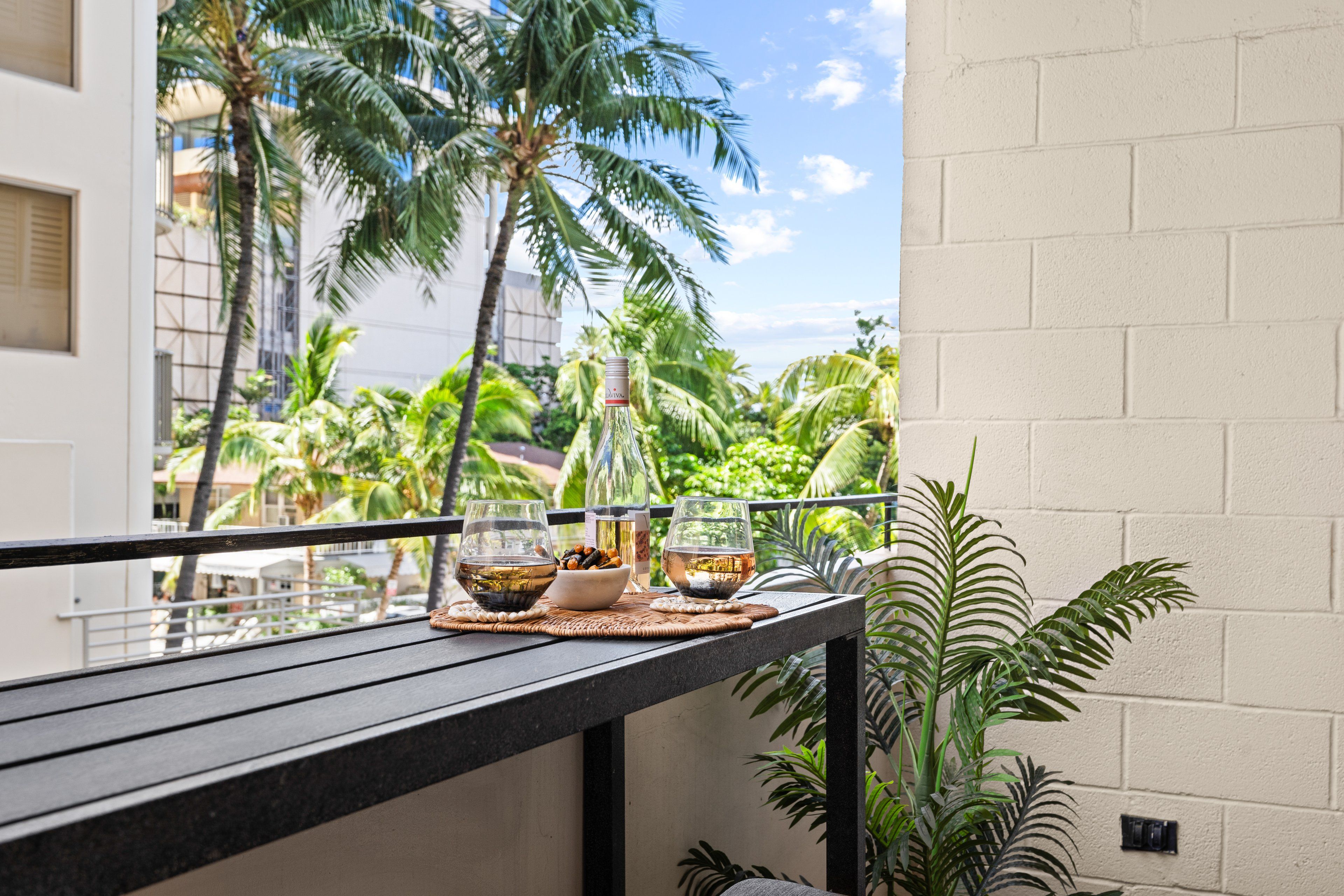 Ein Balkon mit Esstisch, mit Blick auf einen tropischen Garten mit Palmen.