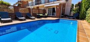 Una piscina con sillones de descanso y un patio.